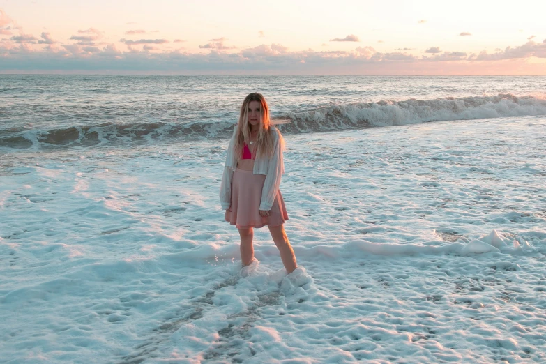 a woman in pink dress standing on ocean beach