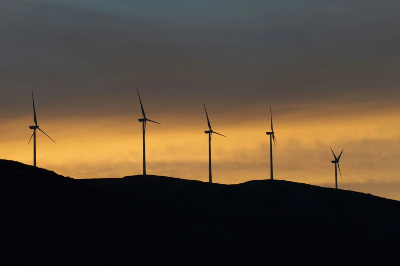 a line of wind turbines on top of a hill