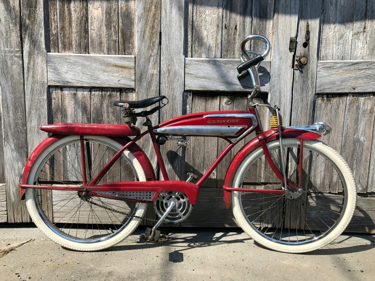 a red bicycle parked in front of a wooden fence