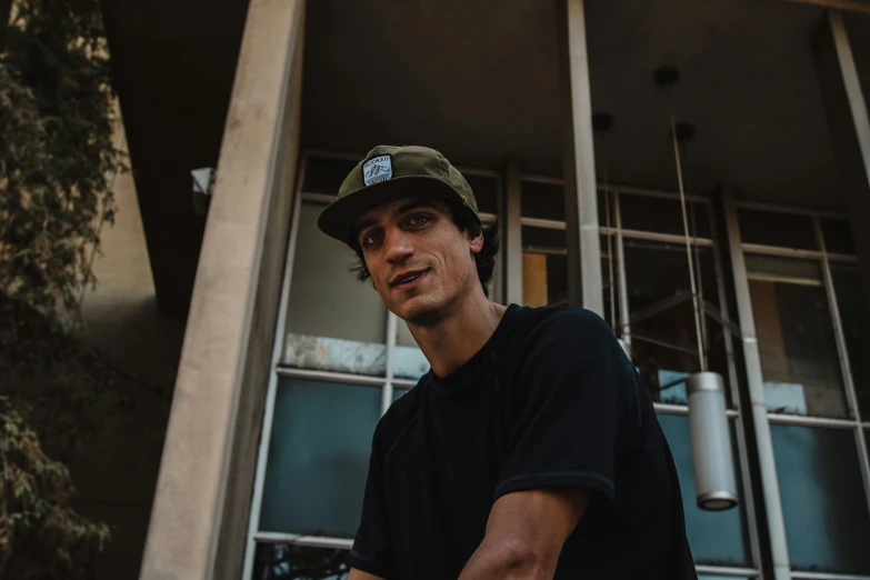 a man standing outside of a building wearing a hat