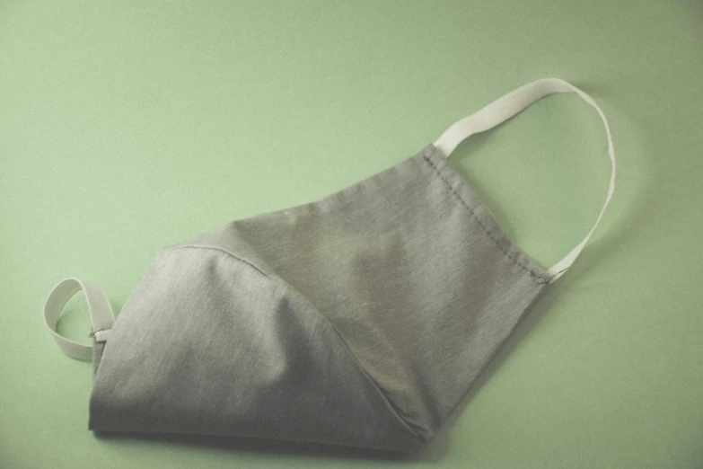 a small gray apron hanging on top of green wall