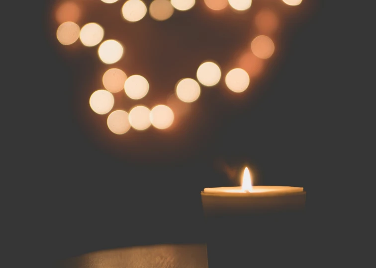 a lit candle sits in front of a heart shaped light