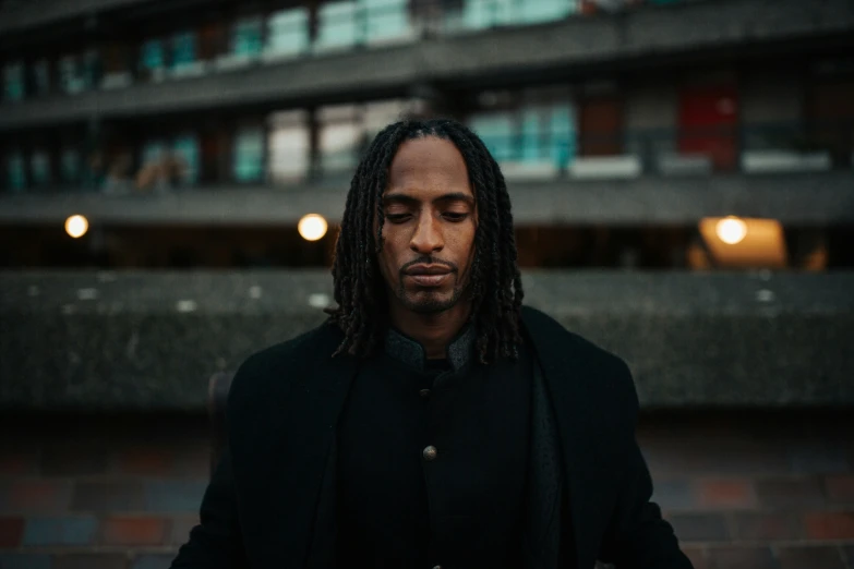 a man with dreadlocks is standing outside in the rain