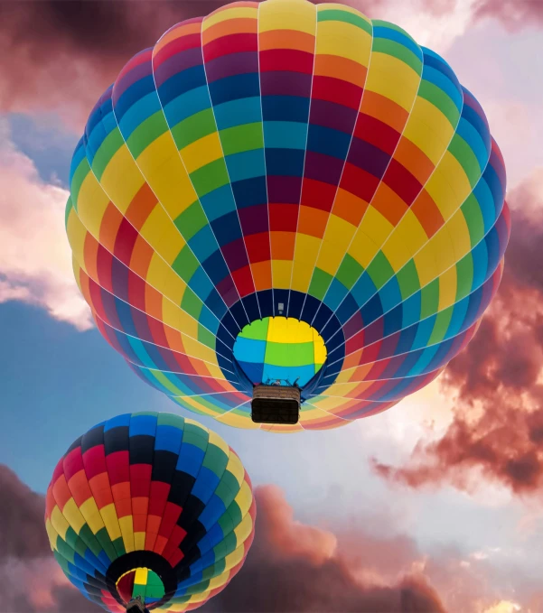 three  air balloons in flight with clouds in the background