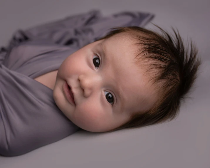 an infant in a gray dress posing for a po