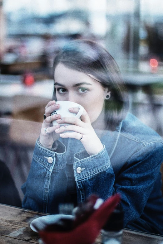 a woman sitting at a table drinking coffee