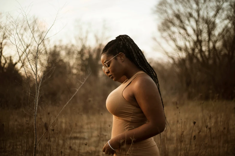 a pregnant woman stands in a field by herself