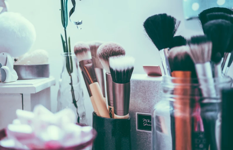 several brushes inside of a jar in the bathroom