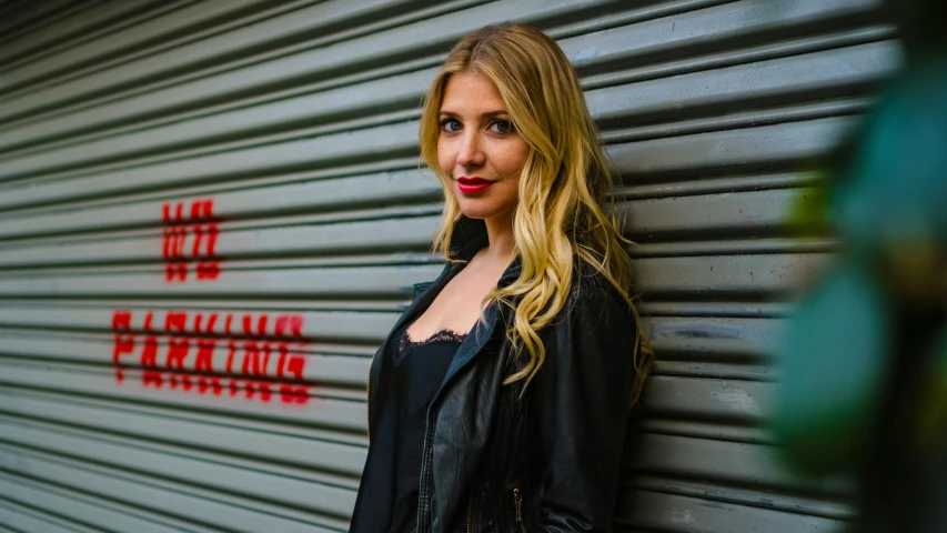 a woman standing against a wall in front of a garage door