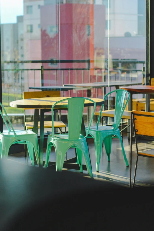 a green patio chair sits next to three rows of yellow tables