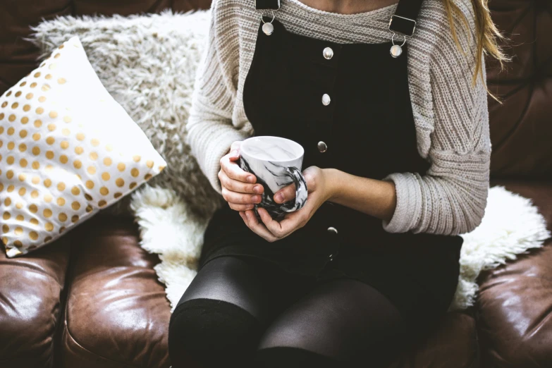 a woman is sitting on the couch with a cup