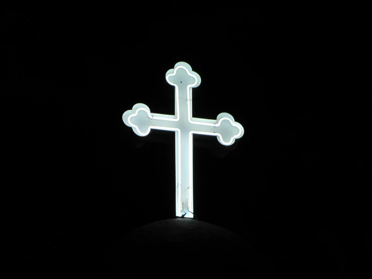 a lighted white cross on top of a black background