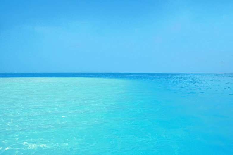 a clear body of water with blue sky and clouds