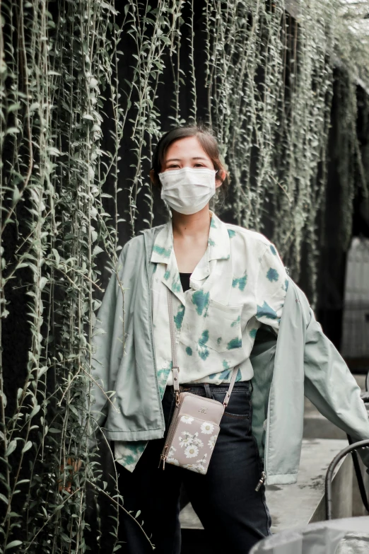 woman in protective mask next to tall bamboo