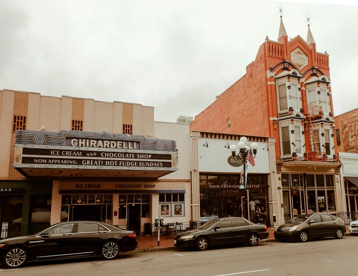 a movie theater on a city street lined with parked cars