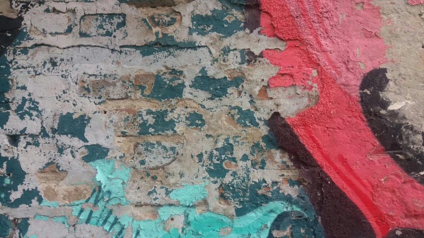an old peeling wall has a piece of red paint on it