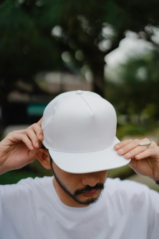 a man wearing a white hat and holding his head up