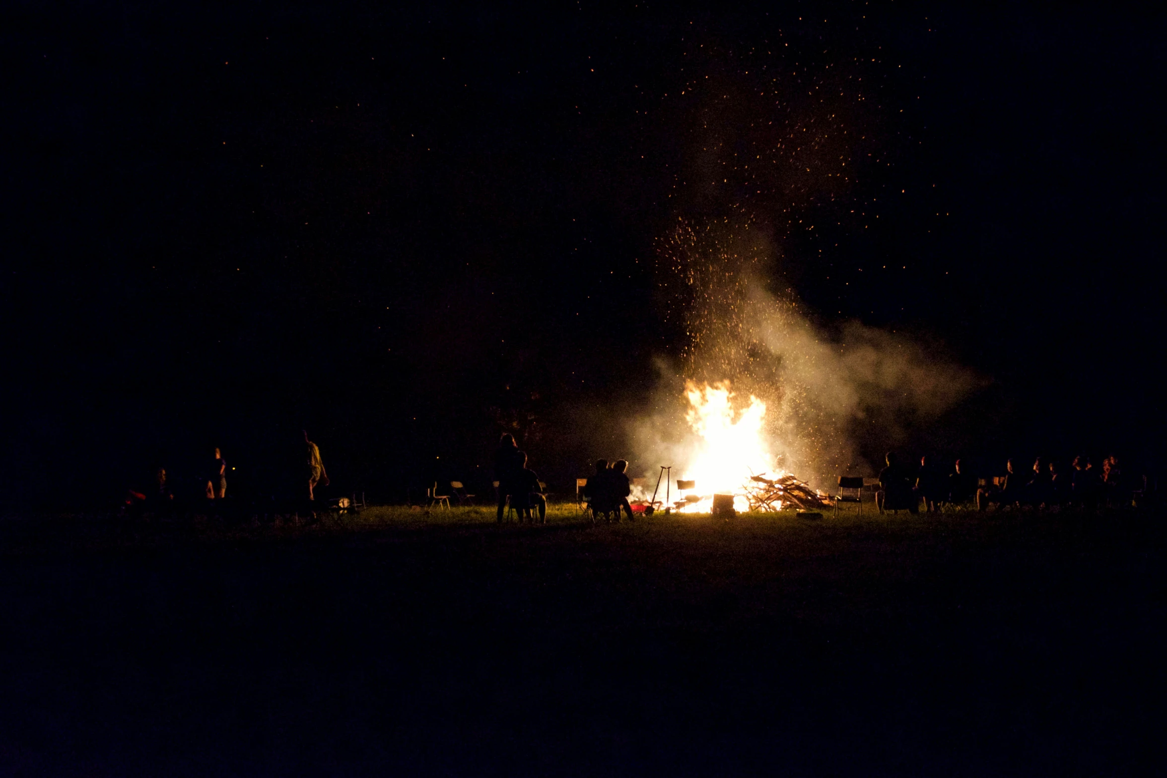 people gather around a bonfire at night with their picture lit
