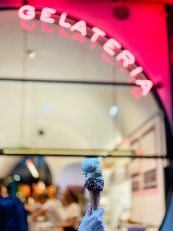 a person holding up a doughnut in front of a building