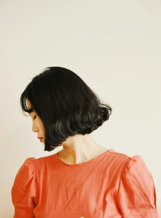 a girl with dark black hair wears an orange top