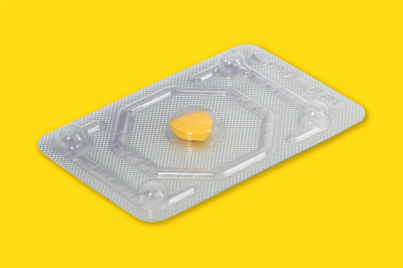 an empty condom case with a yellow pill cap