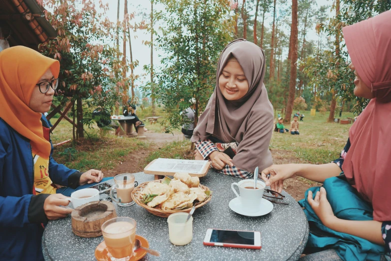 a group of women sitting around a table filled with food