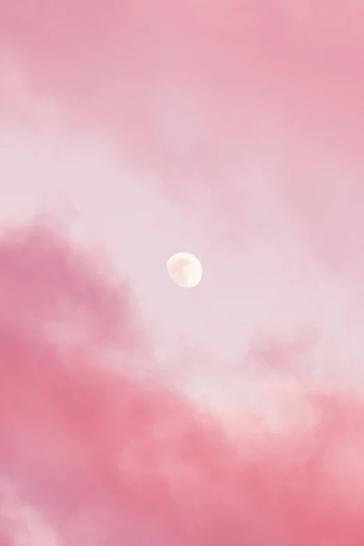 a full moon visible through the pink clouds