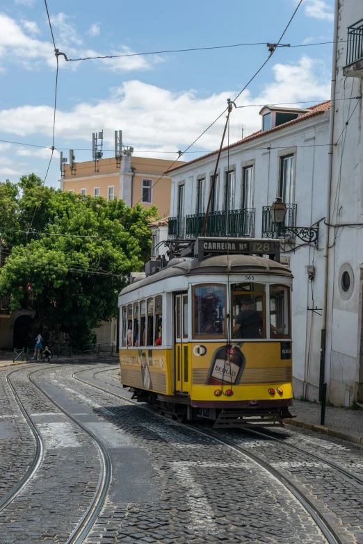 yellow tram with people riding inside down street