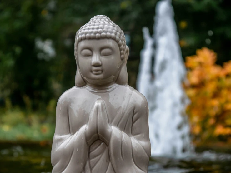 a statue of a person holding the arms of his legs in front of a fountain