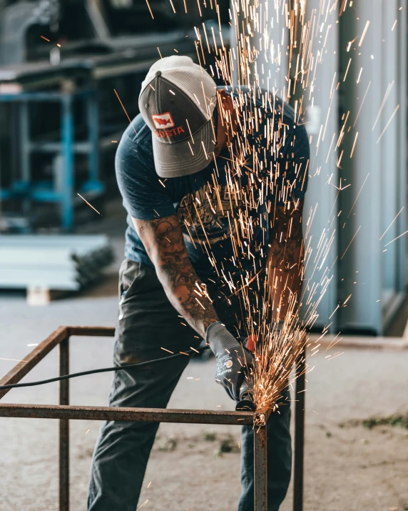 the man is using welding equipment to cut into metal rods