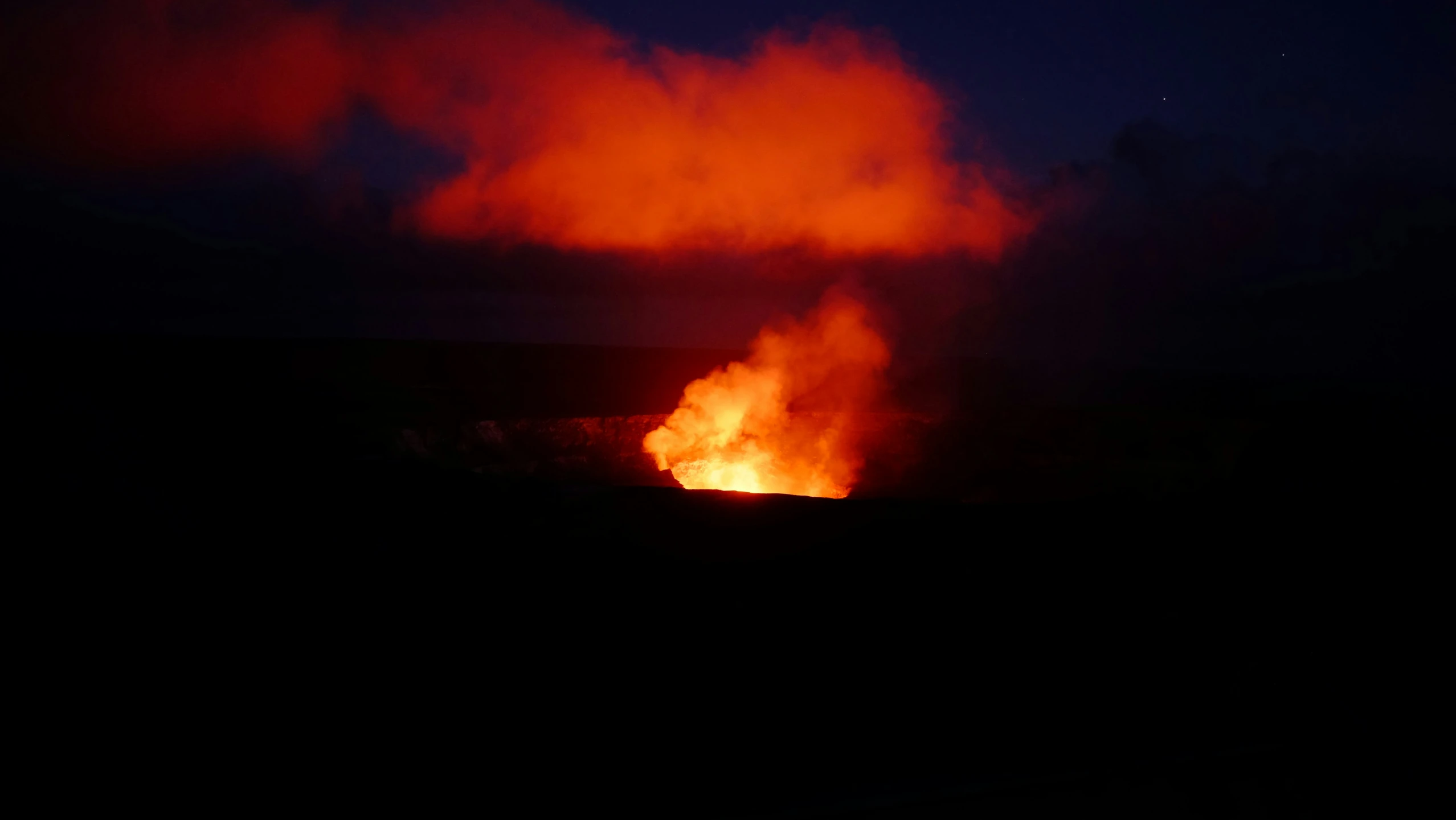 the fire is burning near a field in a dark area