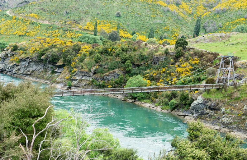 the bridge is high above the water with a stream below it