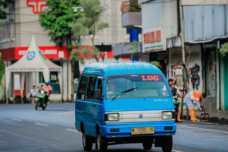 a blue mini van with a white stripe in the road