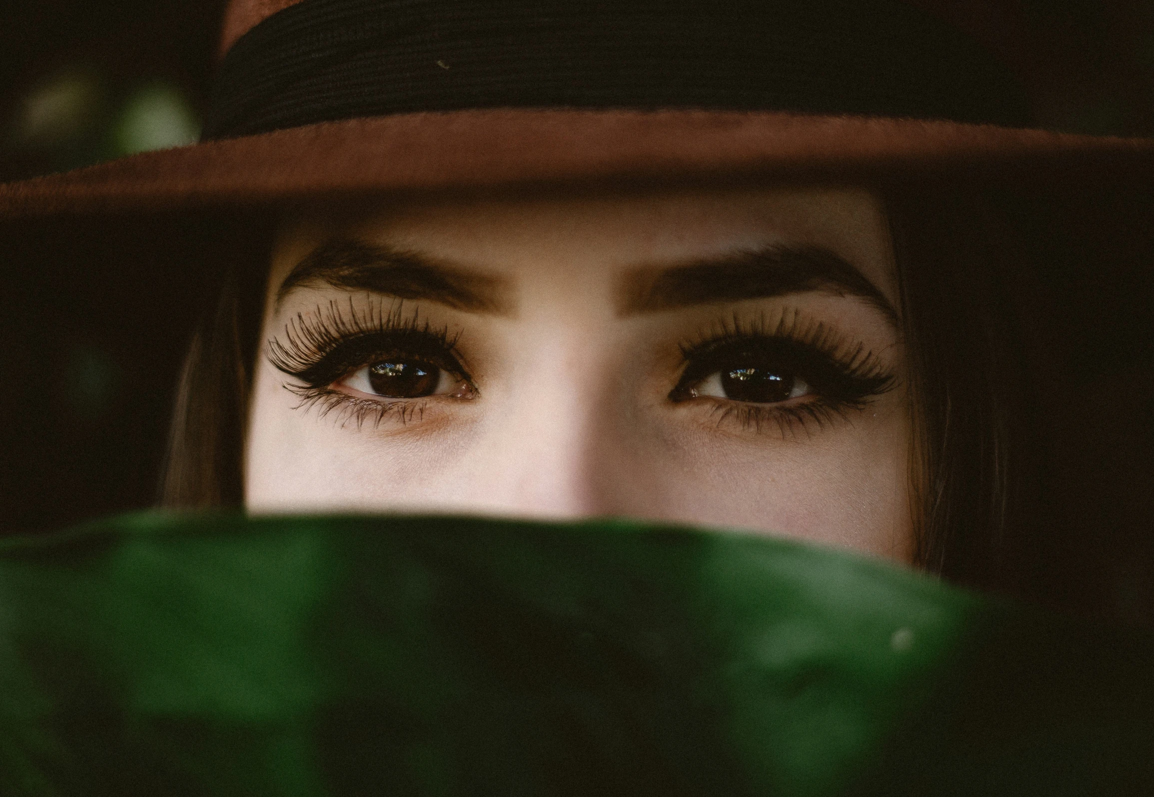 a woman with some very long eyelashes and a brown hat