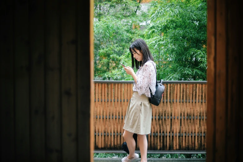 a woman standing looking at her cell phone