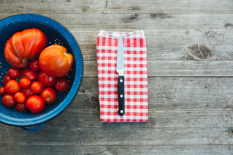 tomatoes, tomatoes and a red checkered napkin sit in a bowl