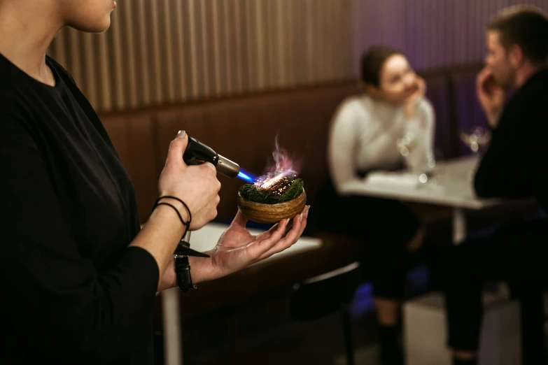 woman holding a torch lighter in her hand while others sit in the background