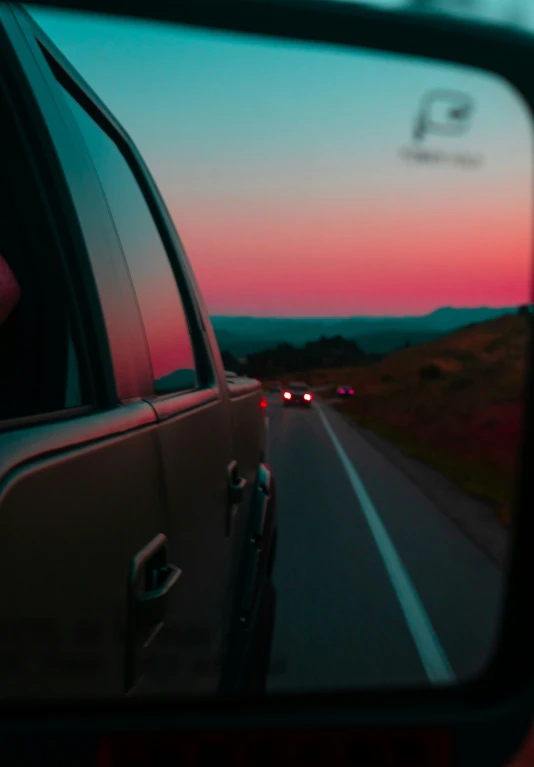 a car window with the reflection of the sun setting in the mirror