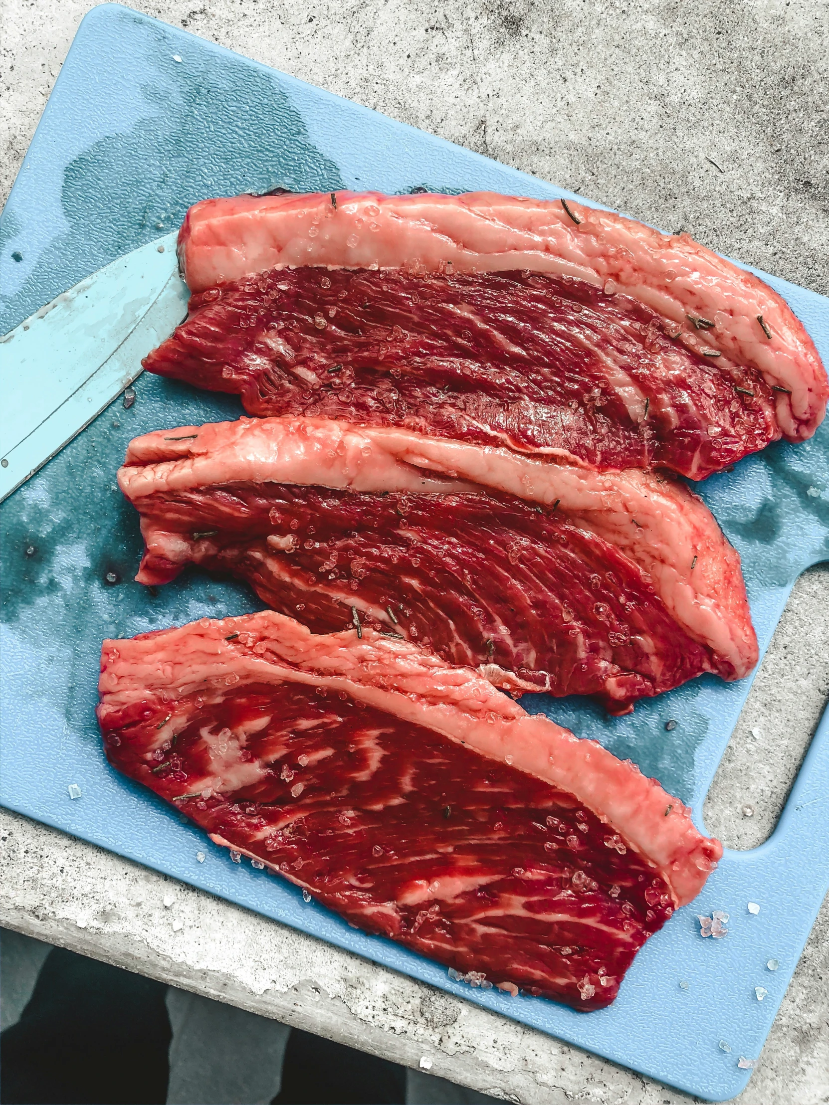 some strips of red meat are on a blue surface