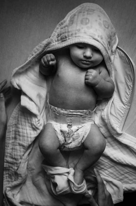 a baby wrapped in a blanket is wearing a diaper