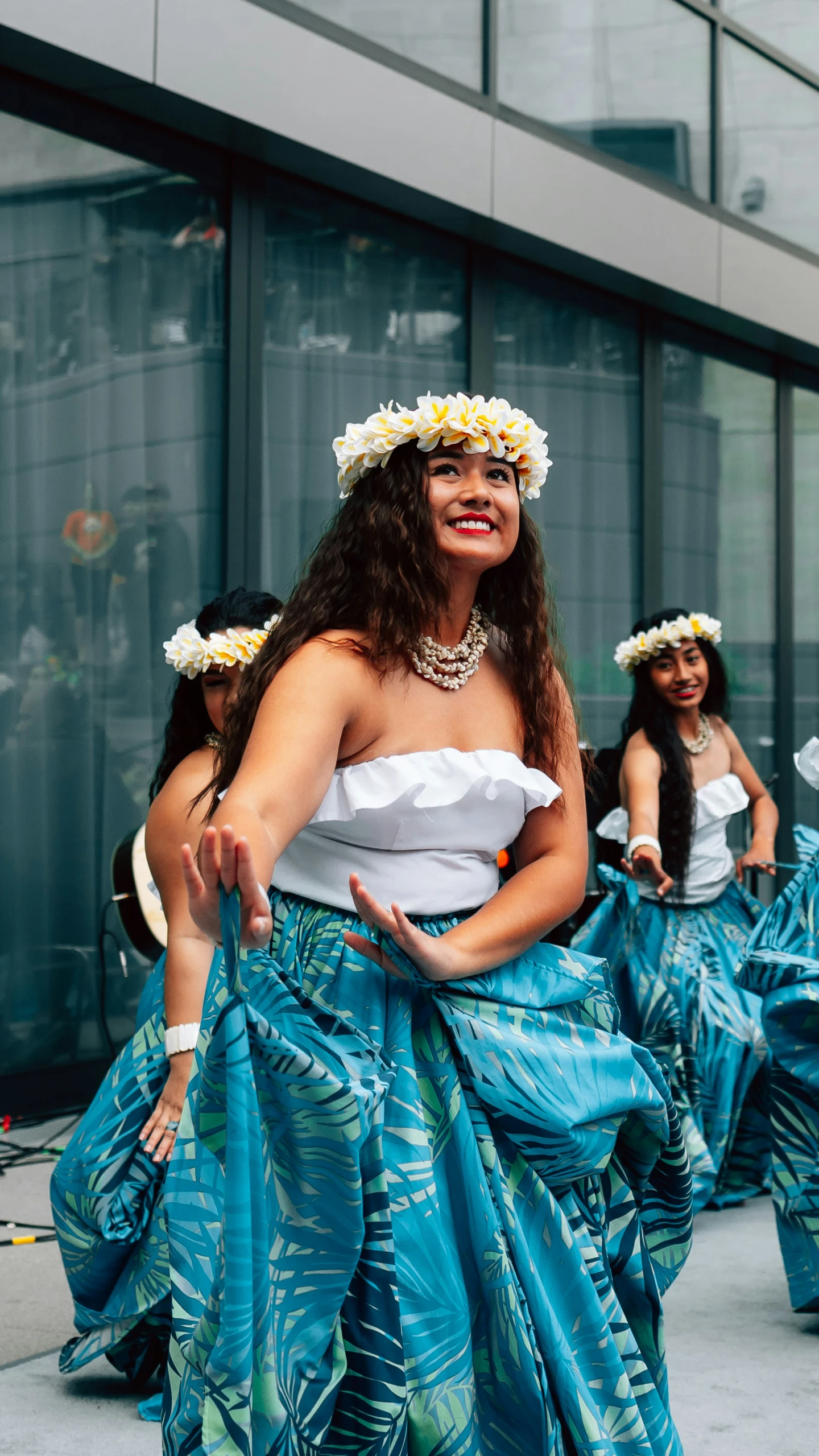 young women in traditional dress dance with palm trees around their heads