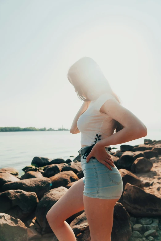 a girl posing on the beach and wearing a hat