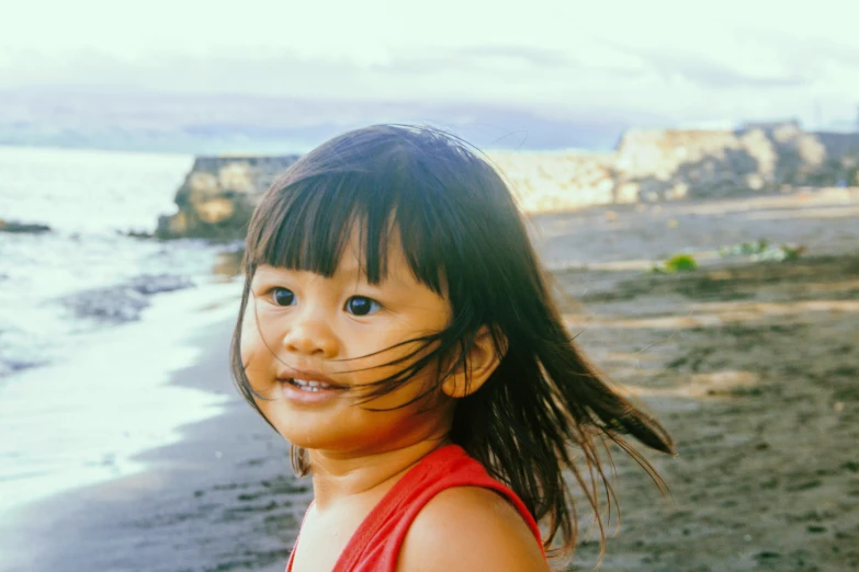 a girl with very thick hair stands near the water