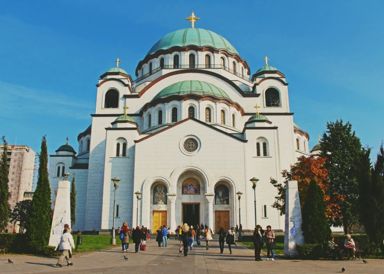 people walking in front of a large white church