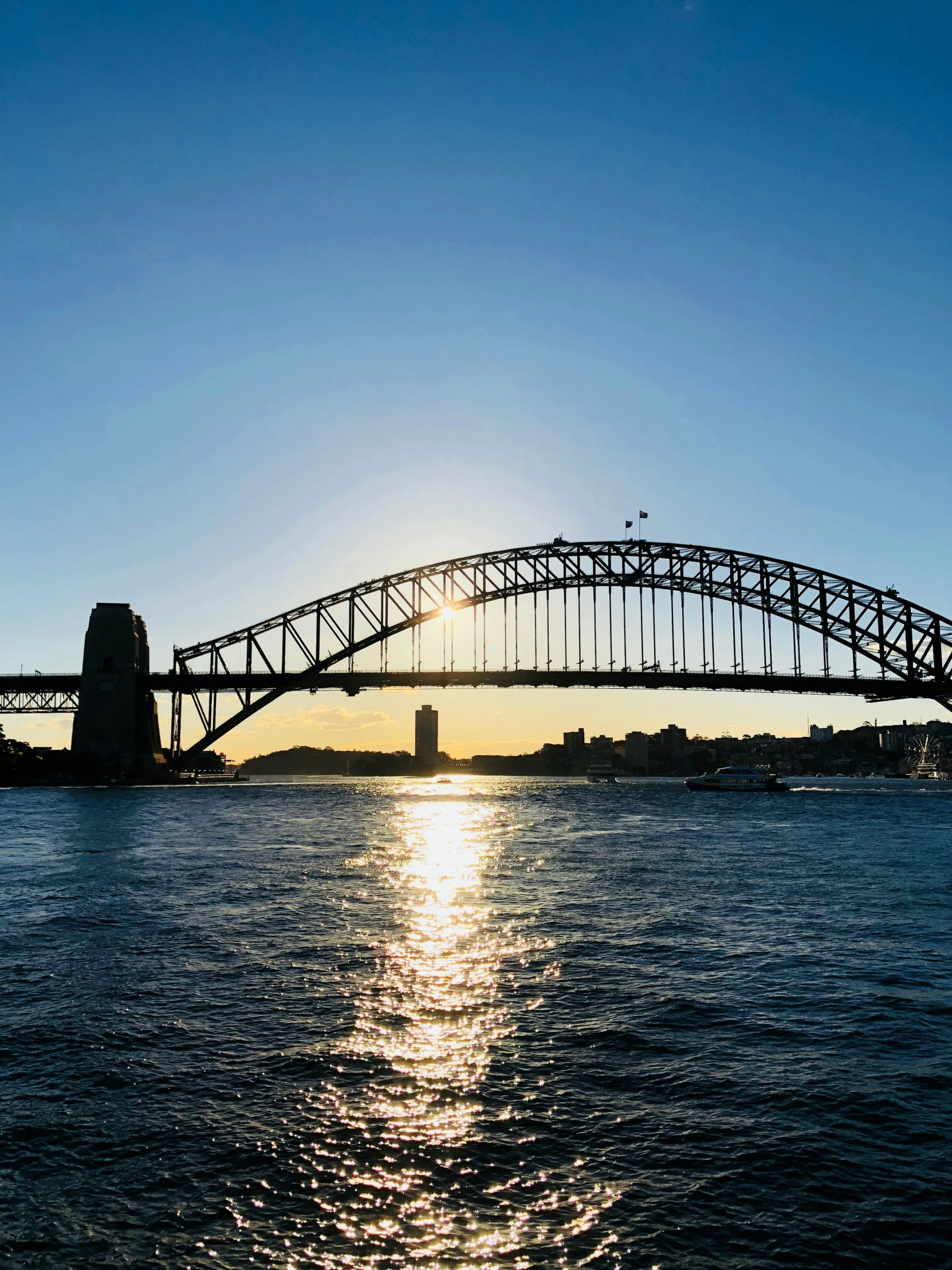 an arch bridge that is over water with the sun setting