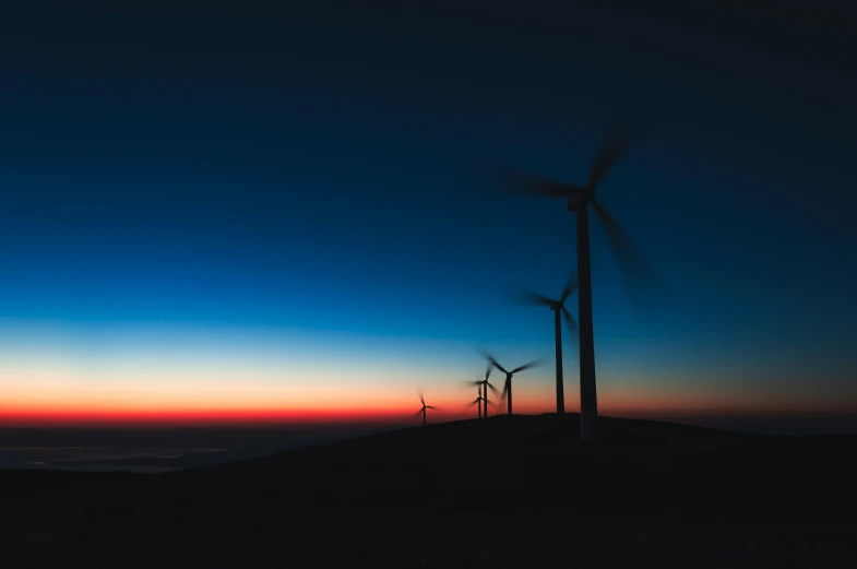 a few windmills sit on the hill and light up the sky