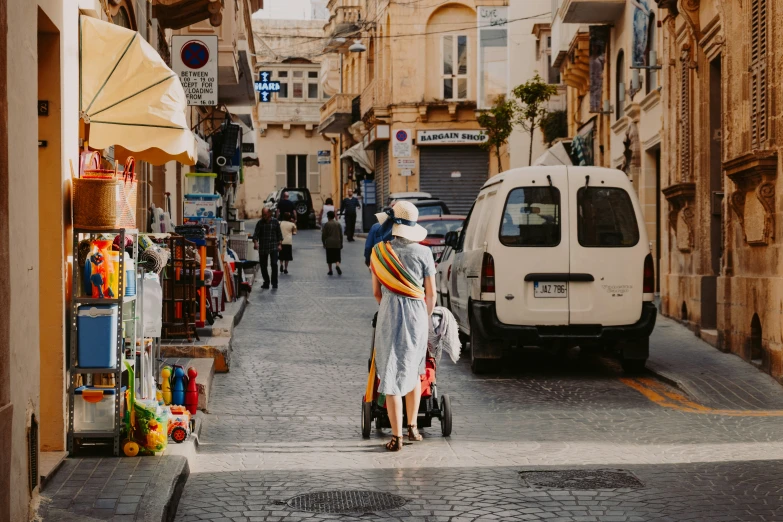 there is a woman with two strollers walking down this street