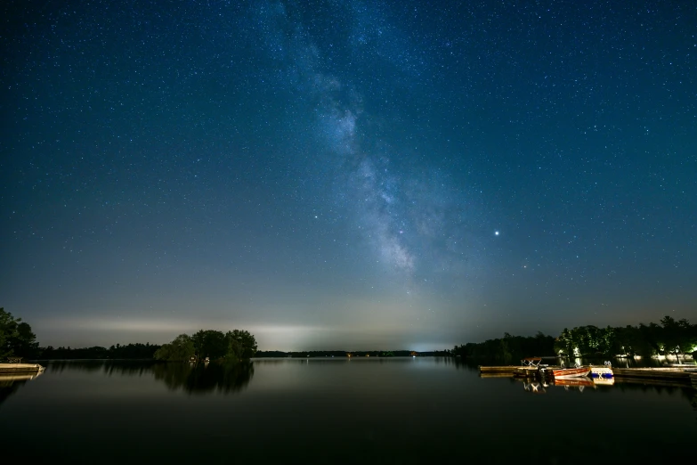 a dark night sky above a river with boats