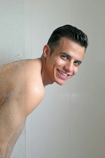 a smiling man with only one shirt on in the shower