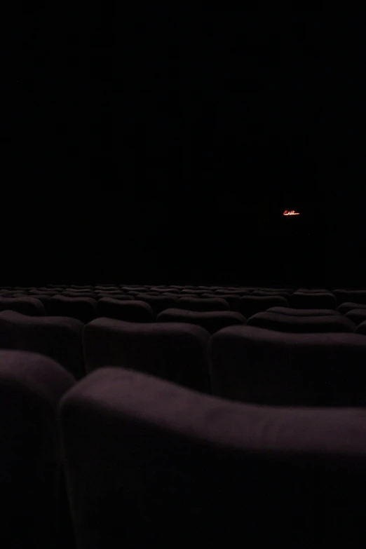 a dark movie theater with seats and bright sign